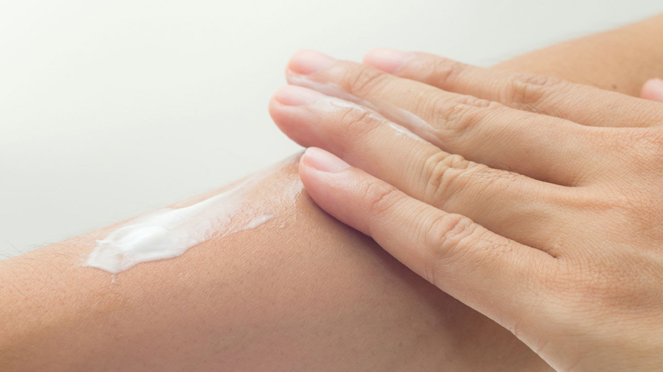 Close-up, hand die crème op de huid smeert